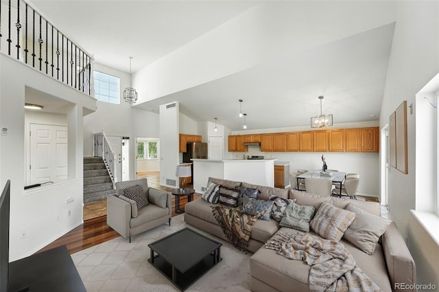 22501 E Belleview Pl, Aurora, CO 80015 - living room featuring stairway, high vaulted ceiling, a chandelier, and light wood finished floors