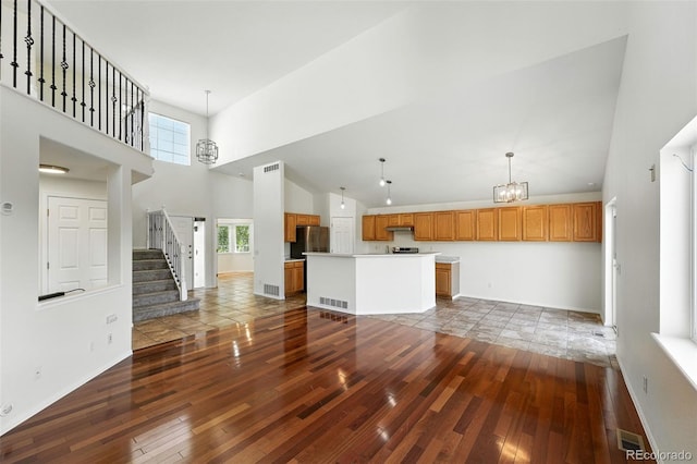 22501 E Belleview Pl, Aurora, CO 80015 - unfurnished living room featuring wood-type flooring, a towering ceiling, a chandelier, and stairway