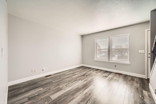 unfurnished room with dark wood-type flooring and a textured ceiling