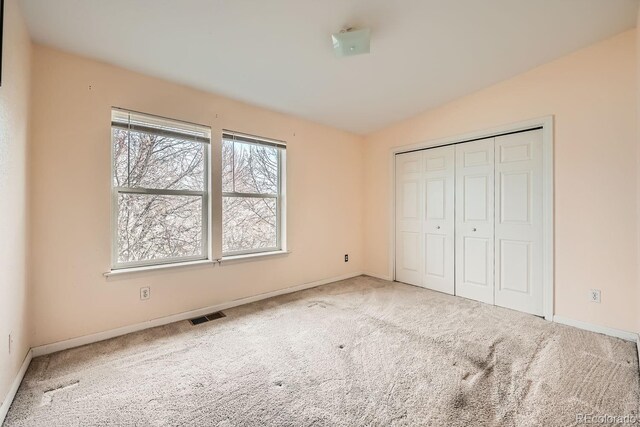 unfurnished bedroom with carpet flooring, vaulted ceiling, and a closet