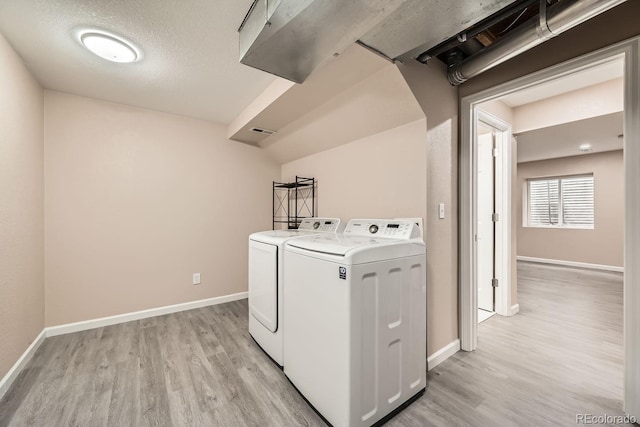 laundry room with light hardwood / wood-style flooring, independent washer and dryer, and a textured ceiling