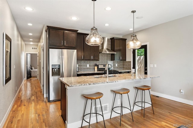 2645 W 24th Ave, Denver, CO 80211 - kitchen with stainless steel refrigerator with ice dispenser, wall chimney range hood, a kitchen breakfast bar, dark brown cabinetry, and decorative backsplash