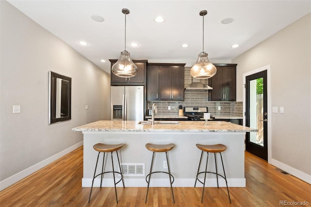 2645 W 24th Ave, Denver, CO 80211 - kitchen with appliances with stainless steel finishes, backsplash, an island with sink, a breakfast bar area, and recessed lighting