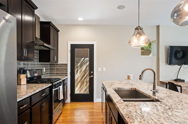 2645 W 24th Ave, Denver, CO 80211 - kitchen with stainless steel appliances, wall chimney exhaust hood, backsplash, light wood-style flooring, and light stone countertops