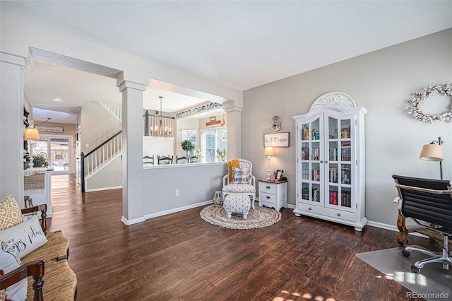 living area with decorative columns, an inviting chandelier, and dark hardwood / wood-style flooring