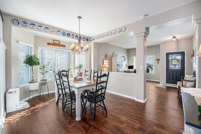 dining space with a textured ceiling, dark hardwood / wood-style floors, decorative columns, and a chandelier