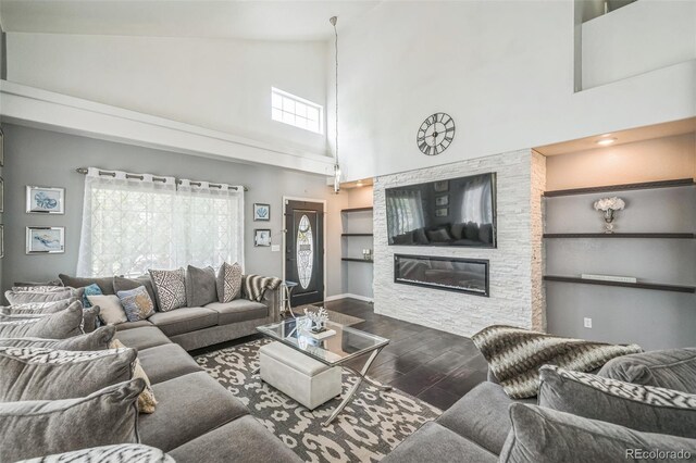20338 E 48th Dr, Denver, CO 80249 - living area with dark wood-style floors, high vaulted ceiling, baseboards, a glass covered fireplace, and built in shelves