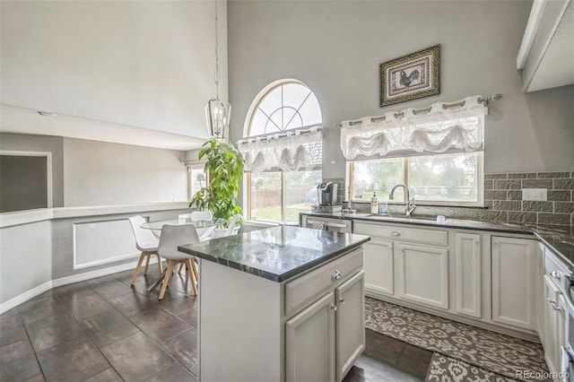 20338 E 48th Dr, Denver, CO 80249 - kitchen featuring a sink, a high ceiling, a center island, decorative backsplash, and dark stone countertops