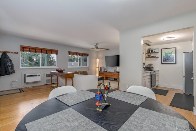 dining room with a wall mounted air conditioner, radiator, light hardwood / wood-style flooring, ceiling fan, and bar