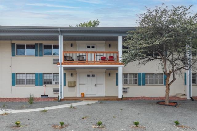 view of front facade with a balcony and an AC wall unit