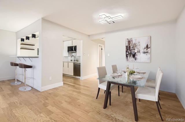 dining room featuring sink and light hardwood / wood-style flooring