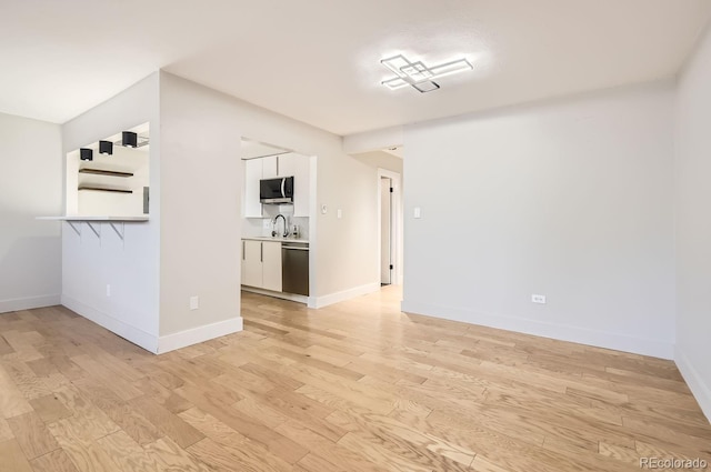 unfurnished room with sink and light hardwood / wood-style floors