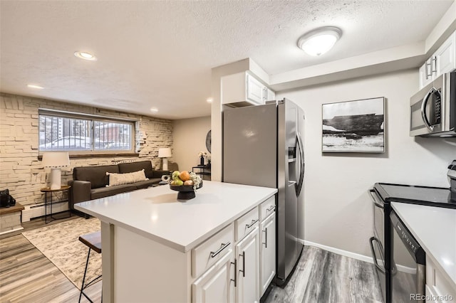 kitchen with appliances with stainless steel finishes, a kitchen bar, a textured ceiling, and white cabinets