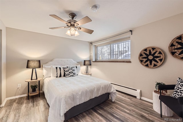 bedroom featuring a baseboard heating unit, wood-type flooring, and ceiling fan