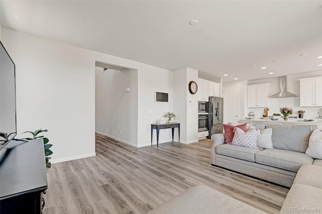 living area with light wood-type flooring, baseboards, and recessed lighting