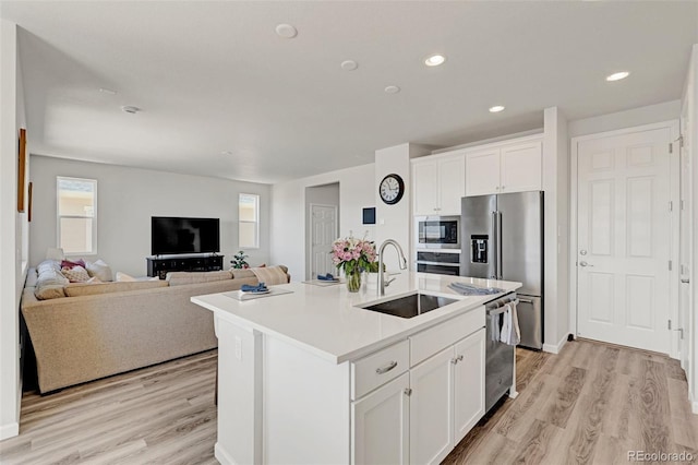 kitchen featuring a sink, stainless steel appliances, white cabinets, light wood-style floors, and recessed lighting