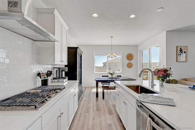 kitchen with wall chimney range hood, stainless steel gas stovetop, a sink, plenty of natural light, and recessed lighting