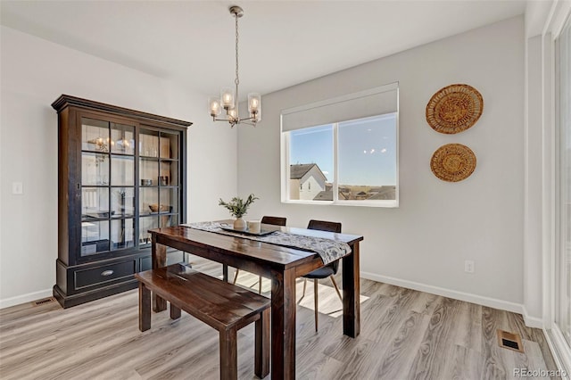 dining room featuring a chandelier, light wood finished floors, and baseboards