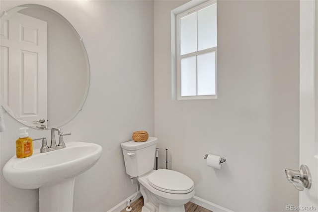 bathroom with toilet, baseboards, a sink, and wood finished floors