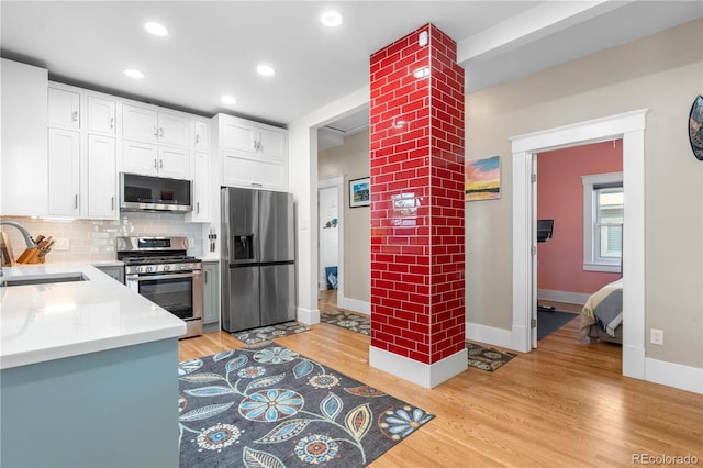 4501 Zenobia St, Denver, CO 80212 - kitchen with appliances with stainless steel finishes, light wood finished floors, light countertops, white cabinetry, and backsplash