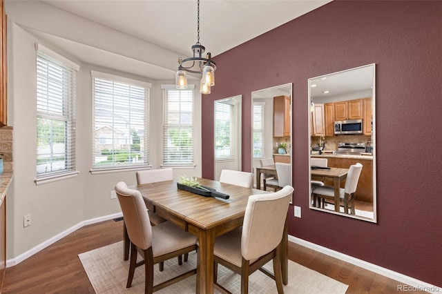 dining space featuring a chandelier, wood finished floors, baseboards, and a textured wall