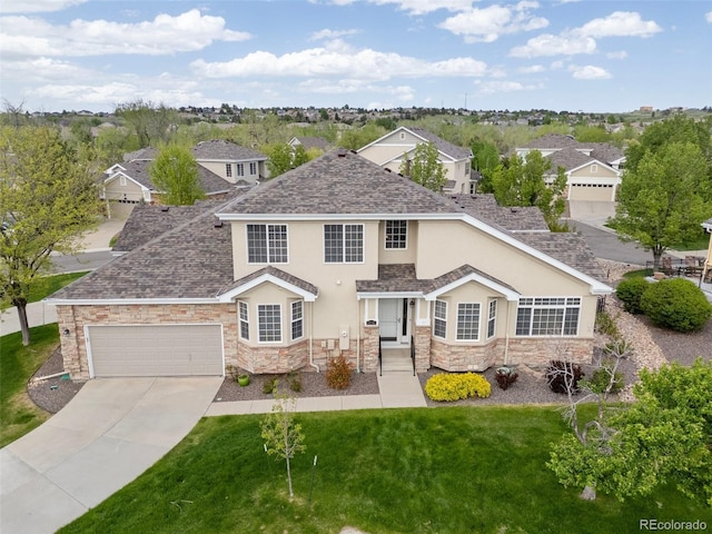traditional-style house with stucco siding, stone siding, concrete driveway, a front lawn, and an attached garage