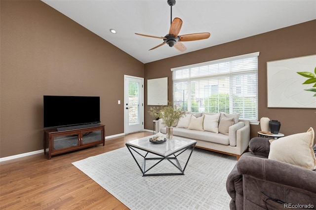 living room with light wood-type flooring, a ceiling fan, baseboards, and vaulted ceiling