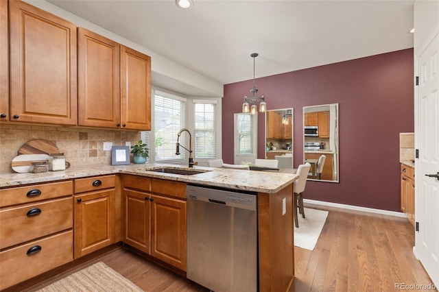 kitchen with stainless steel appliances, a sink, a chandelier, a peninsula, and light wood-type flooring