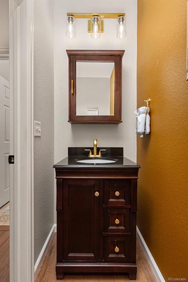 bathroom with wood finished floors, baseboards, and vanity