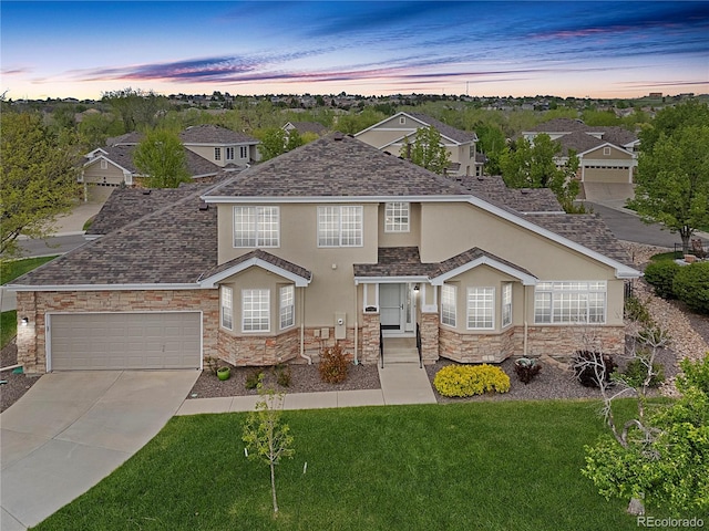 traditional-style home featuring stucco siding, stone siding, driveway, and a lawn