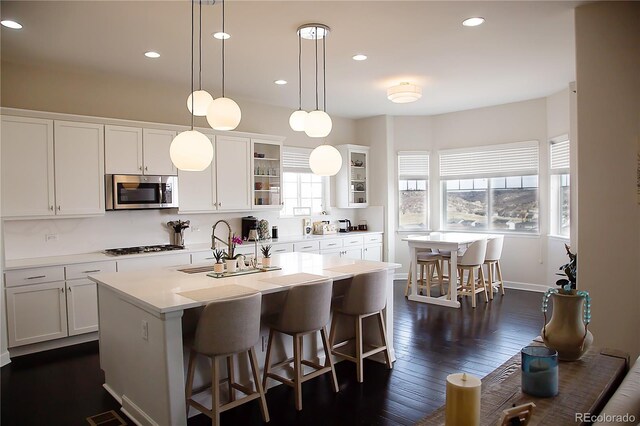 3910 Mighty Oaks St, Castle Rock, CO 80104 - kitchen with stainless steel microwave, a sink, a center island with sink, light countertops, and white cabinetry