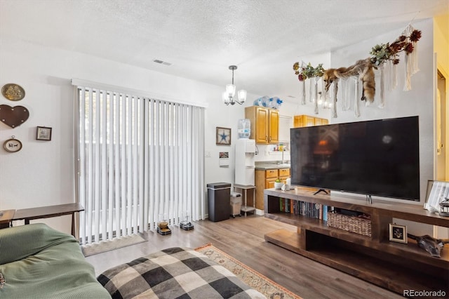 2277 S Buckley Rd Unit 102, Aurora, CO 80013 - living area featuring a chandelier, light wood finished floors, and a textured ceiling
