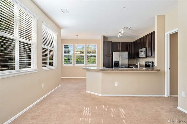 9637 E 5th Ave Unit 101, Denver, CO 80230 - kitchen with appliances with stainless steel finishes, dark brown cabinets, light carpet, a peninsula, and hanging light fixtures