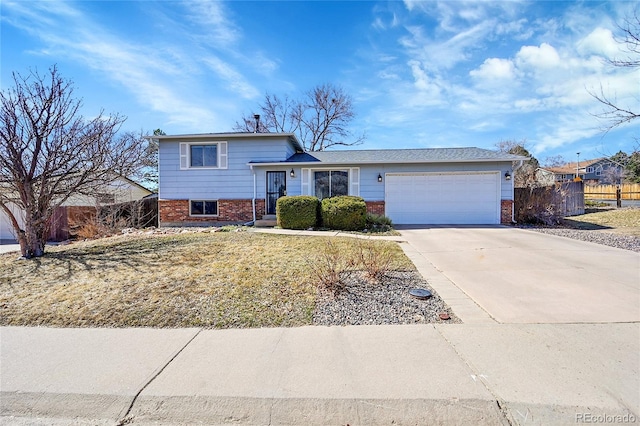 split level home with a garage, brick siding, driveway, and fence