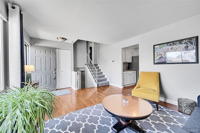 living area with stairway, wood finished floors, and baseboards