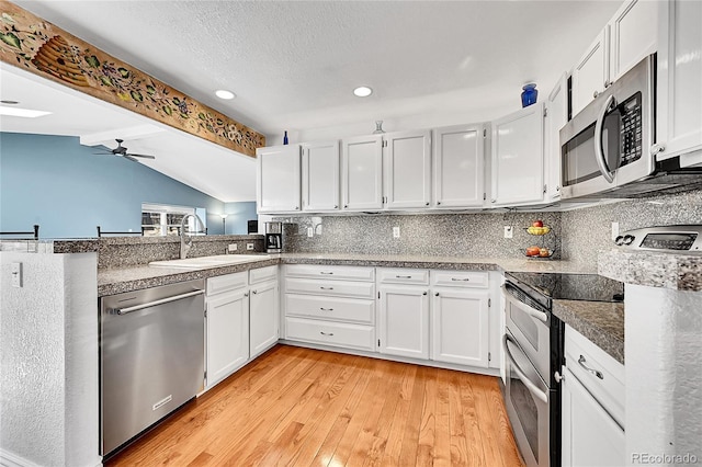 kitchen with a sink, backsplash, stainless steel appliances, ceiling fan, and vaulted ceiling with beams