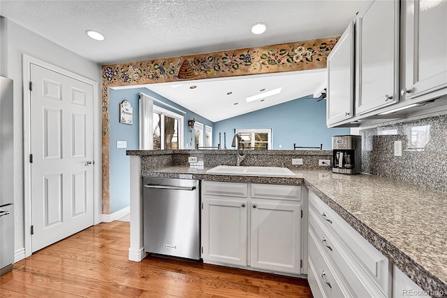 kitchen featuring a sink, vaulted ceiling, tile counters, white cabinetry, and light wood-type flooring