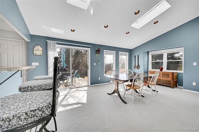 dining space featuring vaulted ceiling with skylight, carpet, and baseboards