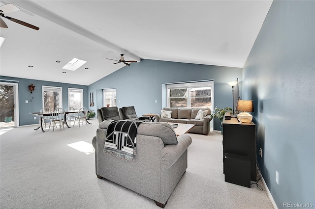 living area featuring vaulted ceiling with skylight, carpet flooring, a ceiling fan, and baseboards