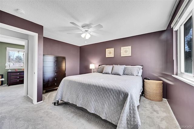 carpeted bedroom featuring ceiling fan, baseboards, and a textured ceiling