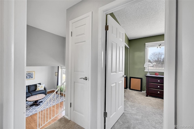 corridor with baseboards, carpet floors, and a textured ceiling