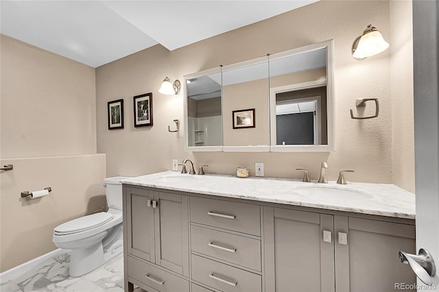 bathroom featuring double vanity, toilet, marble finish floor, and a sink