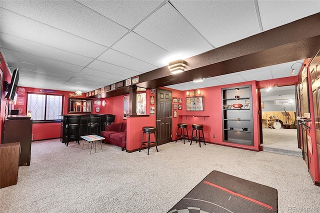 carpeted living room with a dry bar and a drop ceiling