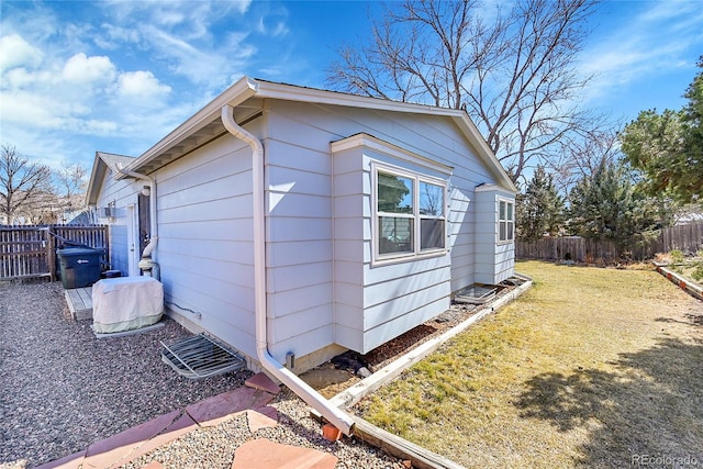 view of home's exterior with a lawn and fence