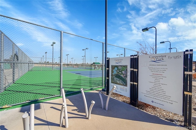 view of property's community with a tennis court and fence