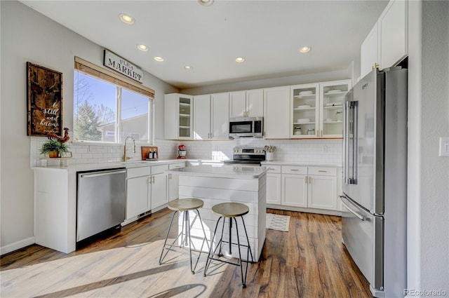 kitchen with tasteful backsplash, a center island, light wood-style floors, stainless steel appliances, and a sink