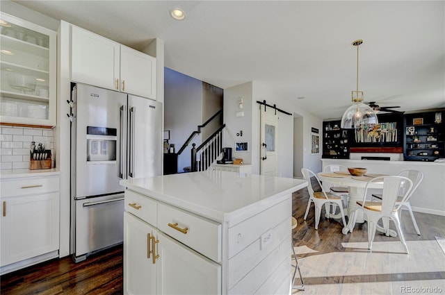kitchen with dark wood-style flooring, a kitchen island, a barn door, and stainless steel refrigerator with ice dispenser