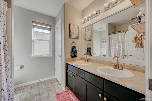 full bath with a sink, baseboards, and double vanity
