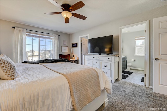 bedroom with light carpet, ensuite bath, multiple windows, and baseboards