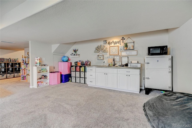 game room with light carpet, visible vents, and a textured ceiling